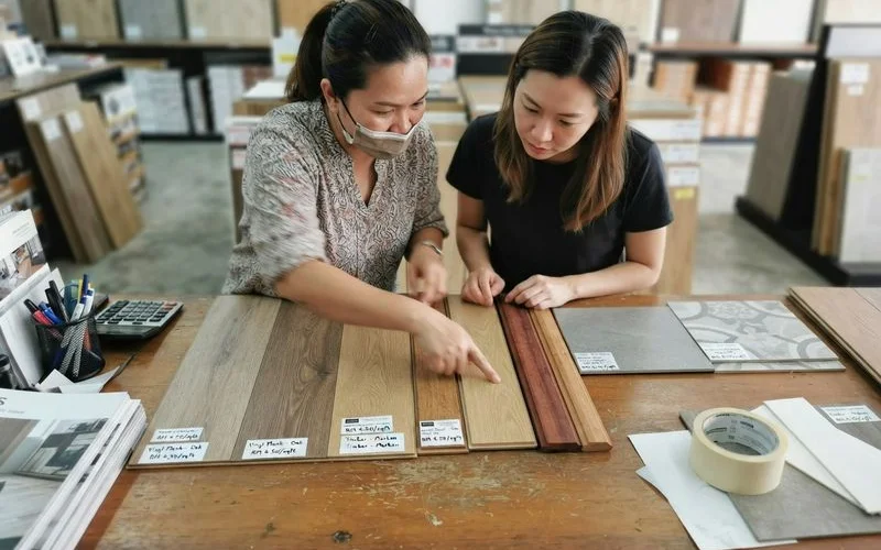 Close-up comparison of vinyl plank, timber and tile flooring samples laid side by side on a table