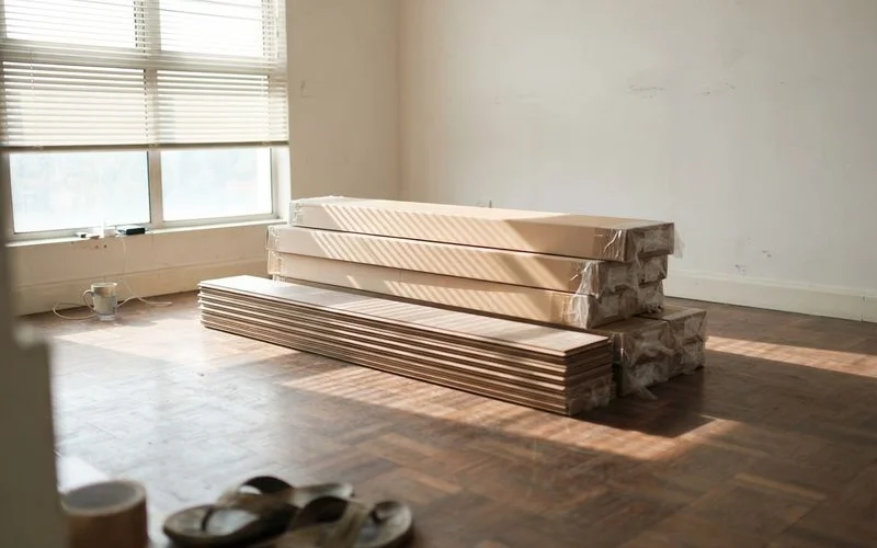 A stack of engineered timber flooring boards acclimating in a Klang Valley living room before installation